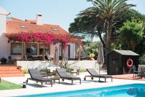 a house with a swimming pool with chairs and umbrellas at Quinta Verde Sintra - Casa de Campo in Sintra