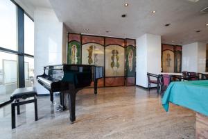 a grand piano in a room with a table and chairs at Hotel Diplomat Palace in Rimini