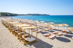 a group of umbrellas and chairs on a beach at Venice Deluxe Studios in Pefkari