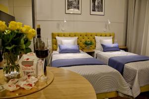 a room with three beds and a table with a glass of wine at Bentis Luxury Apartments in Krakow