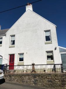 una casa blanca con una puerta roja y una valla en Ard Cashel, Barrack Brae, en Dungloe