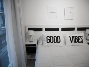 a bedroom with a white bed with good vibes pillows at Studio Esmeralda in Buenos Aires