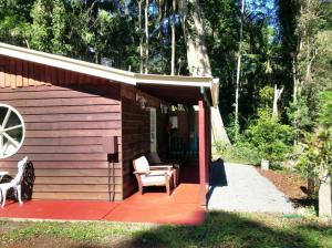 Cabaña pequeña con terraza roja y silla en Curtis Cottage en Mount Tamborine