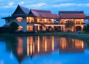 a large house with a pond in front of it at Rico Resort in Chiang Kham