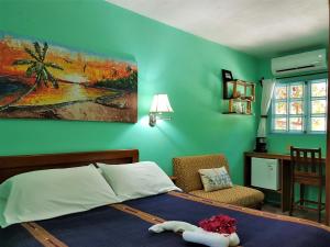 a bedroom with a bed and a chair and a painting at Sea Dreams Hotel in Caye Caulker