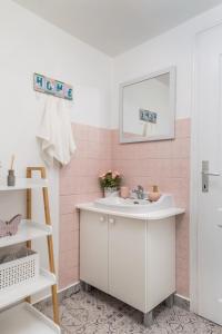 y baño con lavabo blanco y azulejos rosados. en Family House Sara, en Ičići
