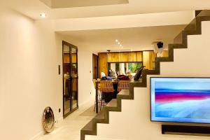 ein Wohnzimmer mit einer Treppe und einem TV in der Unterkunft CASA JUNGLE ! Superb duplex apartment, Place des LICES ! in Saint-Tropez