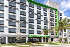 an exterior view of a building with palm trees at Wyndham Garden Ft Lauderdale Airport & Cruise Port in Dania Beach