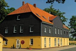 ein gelbes und schwarzes Gebäude mit orangefarbenem Dach in der Unterkunft Landhaus Heidekrug in Hildesheim
