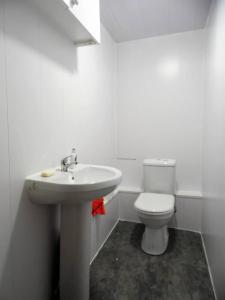 La salle de bains blanche est pourvue d'un lavabo et de toilettes. dans l'établissement 4 Bed Apartment, Paisley - Near GLA Airport, à Paisley