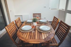 una mesa de madera con sillas, platos y copas de vino en Terradamare en Monopoli