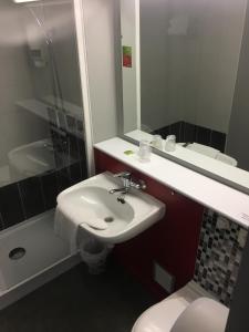 a bathroom with a sink and a toilet and a mirror at Initial by balladins Dieppe in Saint-Aubin-sur-Scie