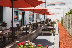 une rangée de tables et de chaises avec parasols sur un bâtiment dans l'établissement Hotel Le Village, à Winnenden