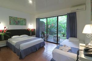 a hotel room with two beds and a balcony at Tirimbina Rainforest Lodge in Sarapiquí