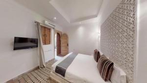 a bedroom with a bed and a tv on the wall at Riad Lamzia in Marrakesh