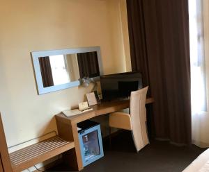 een kamer met een bureau, een computer en een spiegel bij HC3 Hotel in Bologna