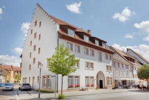 ein großes weißes Gebäude mit einem Baum davor in der Unterkunft Hotel Restaurant Lindenhof in Bräunlingen