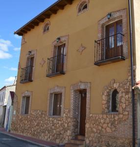 un edificio de piedra con ventanas y balcones en una calle en CASA RURAL LA CIJA, en Maello