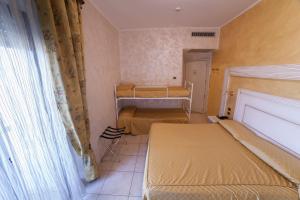 a small room with two beds and a window at Hotel Diplomat Palace in Rimini