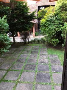 einen Garten mit Bäumen und einem Steingang in der Unterkunft Casa no coração de gramado in Gramado