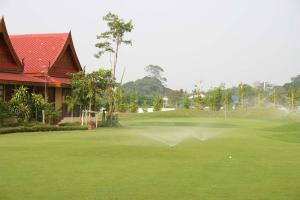 a golfer hitting a ball on a golf course at Rico Resort in Chiang Kham