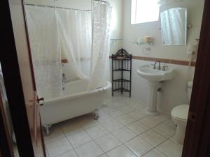 a bathroom with a tub and a toilet and a sink at Manresa Castle in Port Townsend