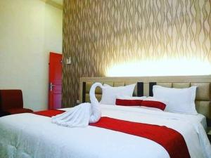 Dos camas en una habitación de hotel con un cisne. en Hotel Assyifa Tanjungbalai, en Tanjungbalai