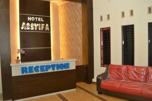 un vestíbulo con un sofá de cuero rojo en la recepción del hotel en Hotel Assyifa Tanjungbalai, en Tanjungbalai