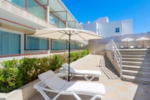 due sedie e un ombrellone accanto a un edificio di Hostal Molins Park a Ibiza Città