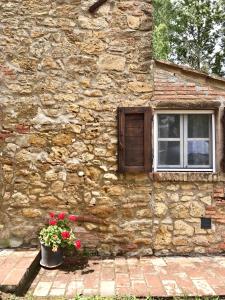 um edifício de pedra com uma janela e um vaso de flores em Le Casette em Guardistallo