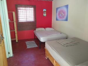 duas camas num quarto com paredes vermelhas em Conrado's Guesthouse B&B em Las Avispas