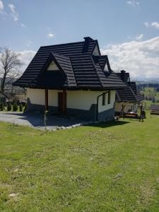 a house with a black roof on a green field at Domki z widokiem na Tatry in Bańska