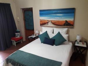 a bedroom with a white bed and a painting on the wall at Relax in Joy & Mignon for a bushveld Feeling in Bloemfontein
