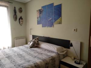 1 dormitorio con 1 cama y algunas fotos en la pared en Bordatxiki, en Hondarribia