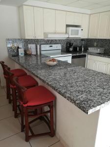 a kitchen with a granite counter top and red chairs at Grand Marina Villas in Nuevo Vallarta