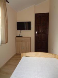 a bedroom with a bed and a flat screen tv at Otthon Apartman in Hajdúszoboszló