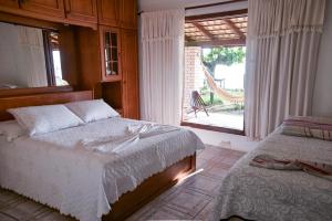 a bedroom with a bed and a window with a chair at Recanto dos Machados in Saudades