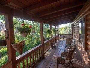 a porch of a cabin with chairs and flowers at Canyon Wren Bed and Breakfast in Bluff