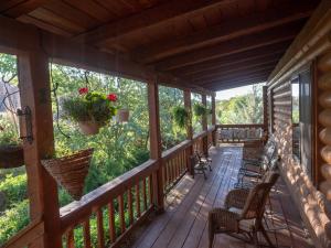 un porche de una cabaña con sillas y flores en Canyon Wren Bed and Breakfast, en Bluff