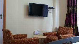 a waiting room with two chairs and a flat screen tv at Flyer Exotica in Shimla