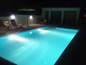 a swimming pool at night with an umbrella and chairs at B&B Casa Encantada in Boliqueime