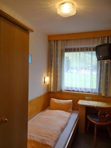 a small room with a bed in front of a window at Ski & Bike Pension Maria in Saalbach Hinterglemm