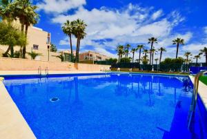 una gran piscina azul con palmeras en 40 Kate el Coral - Alicante Real Estate, en La Mata