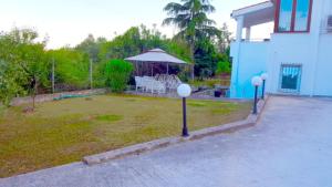 ein Haus mit einem Hof mit einem Tisch und einem Sonnenschirm in der Unterkunft Blue Appartment in Nea Iraklitsa