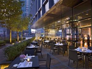 ein Restaurant im Freien mit Tischen und Stühlen und ein Gebäude in der Unterkunft Grand Millennium Beijing in Peking