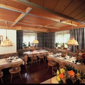un ristorante con tavoli e sedie con fiori di Ski & Bike Pension Maria a Saalbach Hinterglemm