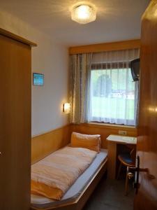 ein kleines Bett in einem Zimmer mit Fenster in der Unterkunft Ski & Bike Pension Maria in Saalbach-Hinterglemm