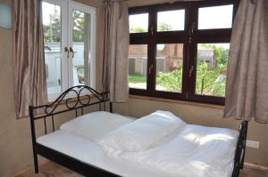 a bed with white pillows in a room with windows at Ferienhaus Caselow 23 in Bergholz