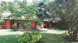 an orange building with trees in front of a yard at Pousada Rancho da Mata in Conservatória