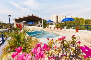 a swimming pool with blue umbrellas and pink flowers at Hotel Suites Ixtapa Plaza in Ixtapa